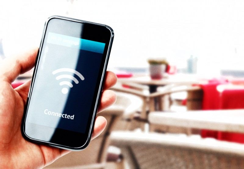 Hand holding smartphone with wi-fi connection in cafe