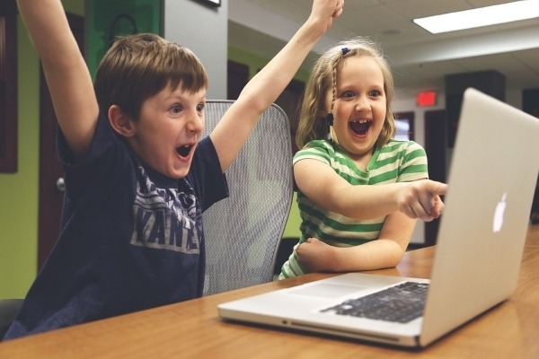 images of kids happily looking at laptop screen